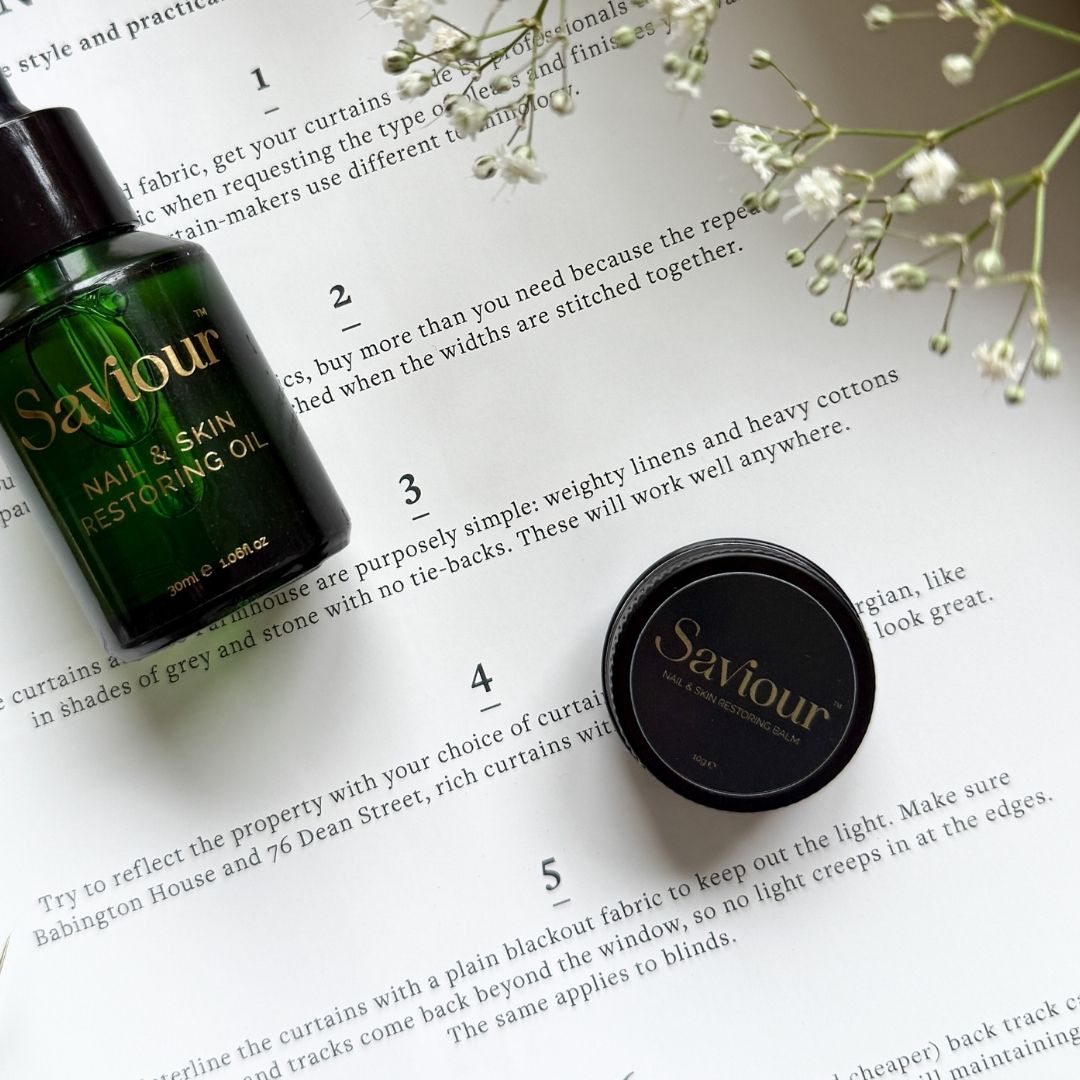 Savour nail and skin restoring oil bottle and cap on a book page with flowers.