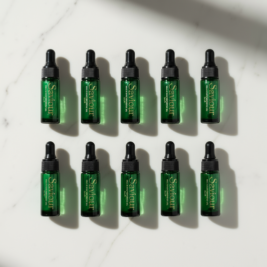 10 mini cuticle and skin oils, in green glass bottles on a white marble background